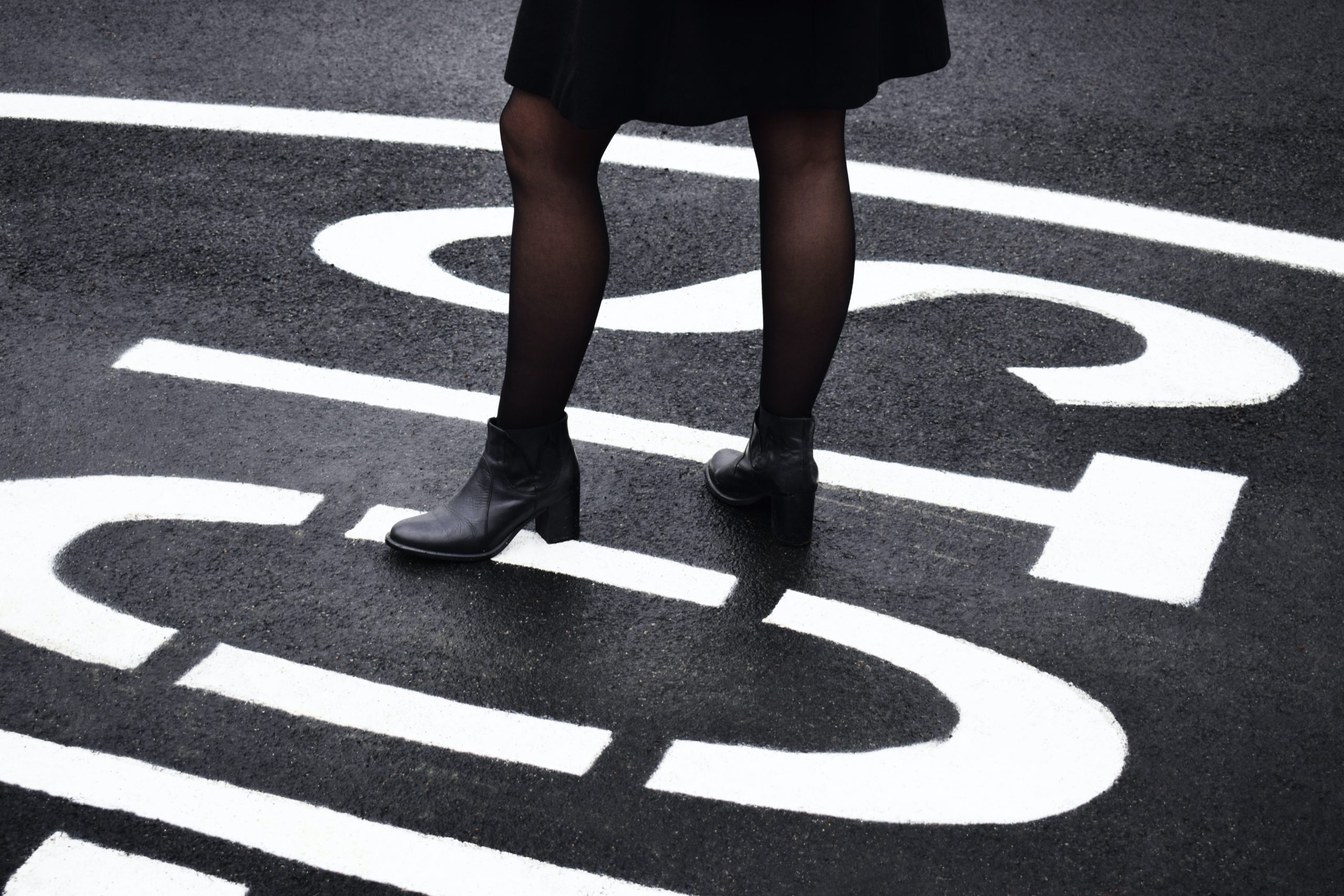 woman standing over the word stop on black asphalt